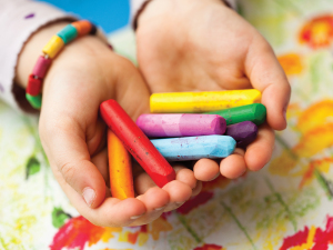 Close-up of child holding colorful wax crayons in hands